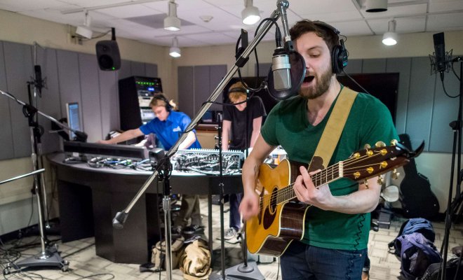 Students record a singer in the studio.