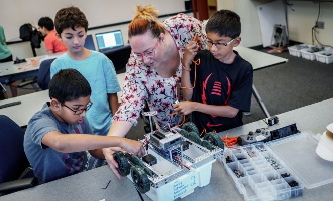 Young students work on a robotic car alongside a teacher on the campus of Montclair State University.