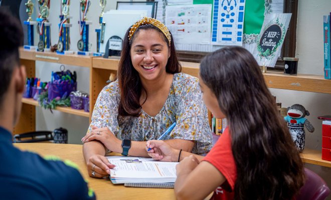 A teacher works on reading with a younger student.