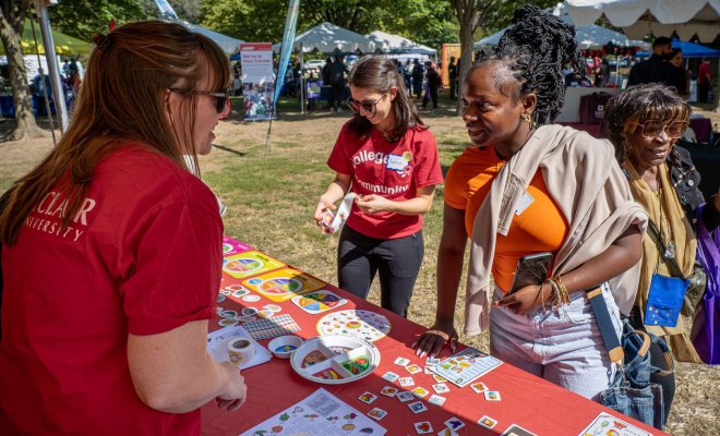 A student at an outdoor fair hands out information about nutrition to attendees.