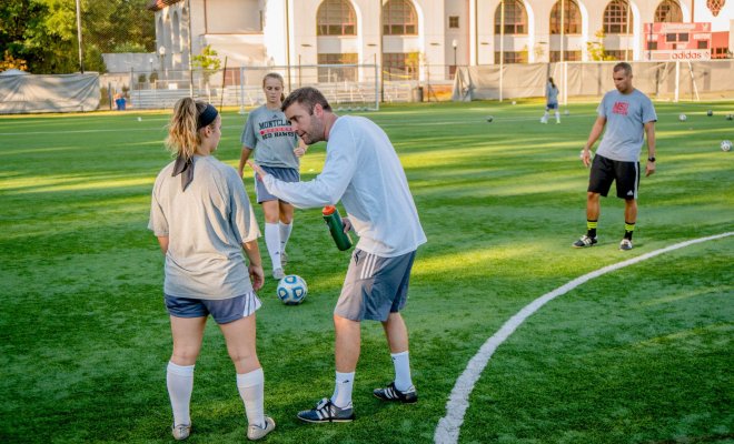 A soccer player receives coaching on the field.
