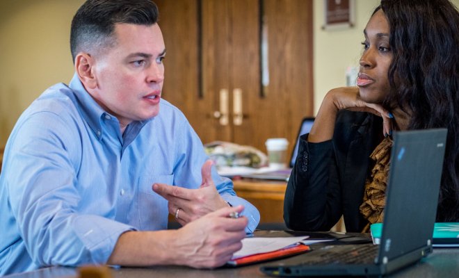 Two students converse over notes in a collaborative workspace.