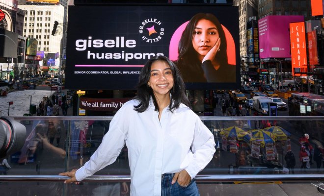 Giselle Huasipoma stands in front of a digital billboard in Times Square