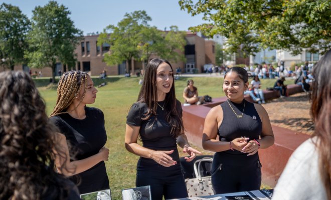 Three females at a Greek Event behind a table.
