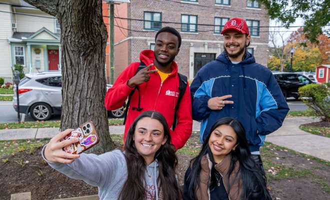 Four students are taking a selfie on campus.