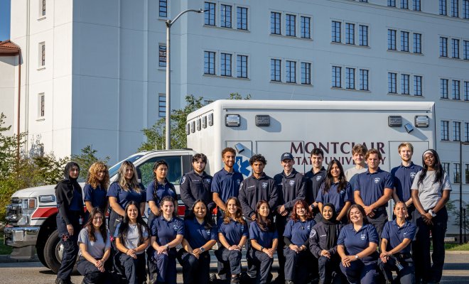 Group of EMS students in front of an ambulance with Montclair State University on the side of the truck.