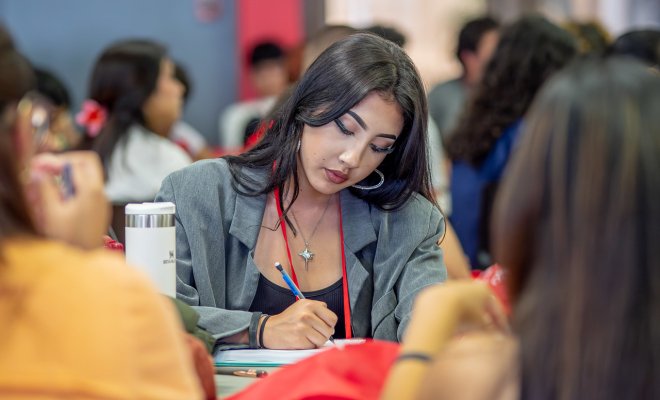 Female student is writing down something on her notebook.