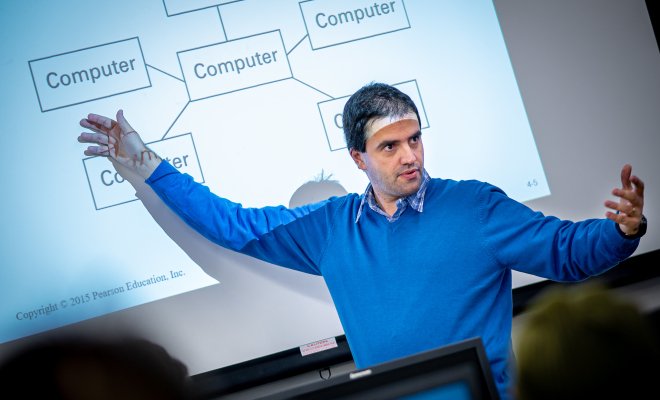 Professor in front of a projector pointing at a computer diagram.