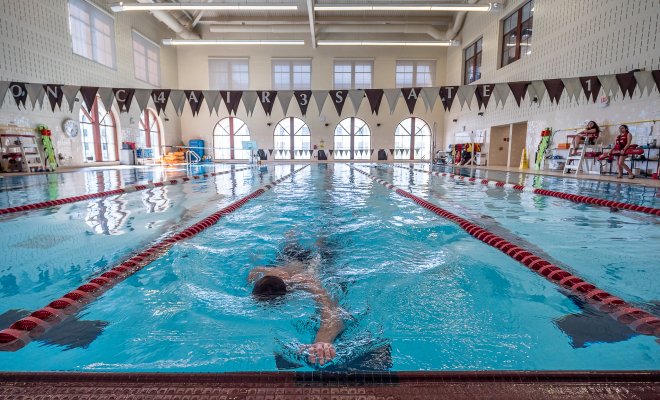 Male swimming in pool in between a line divided by red constructs. 