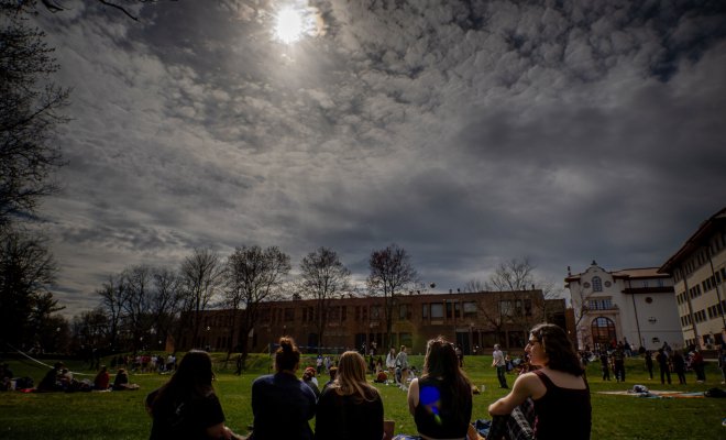 Students sat down on the quad looking at the Eclipse.