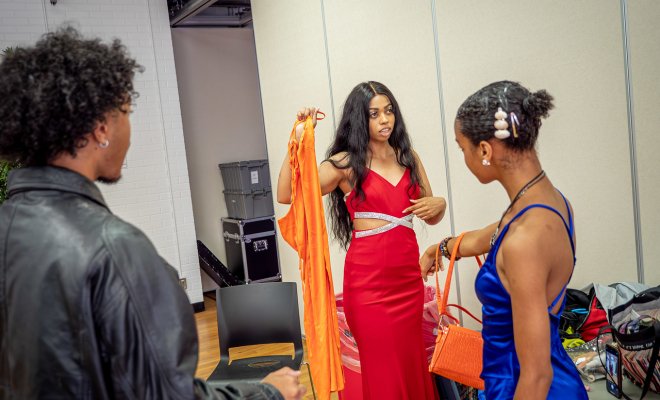 Students are discussing dresses while wearing them for a fashion show.