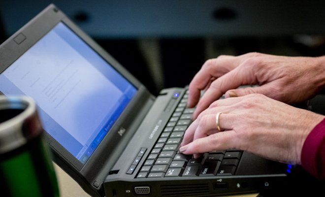 Someone typing on laptop with a ring on their finger.