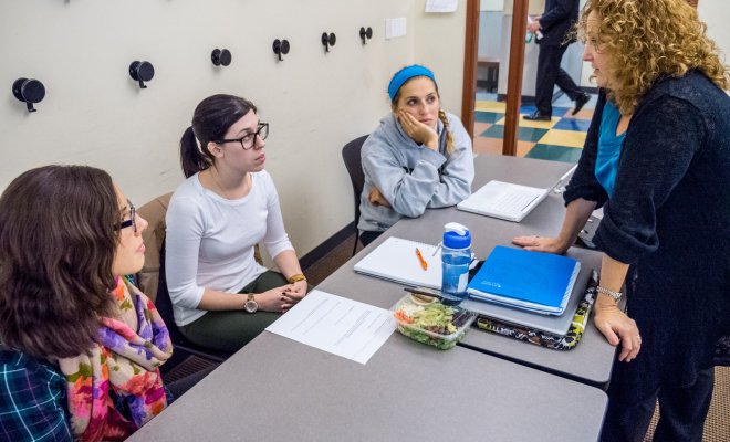 Students in a classroom listening closely to their professor explain. 