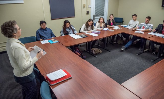Professor reading a book alongside her class, fill of student in a square shape.