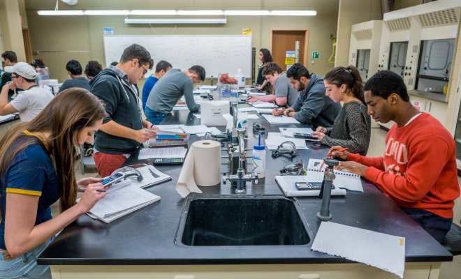 Classroom full of students in a chemistry lab focused.