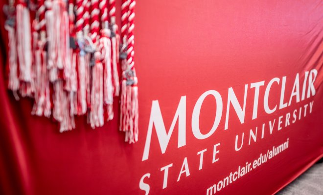 Red banner with the words Montclair State University and red tassels haninging off.