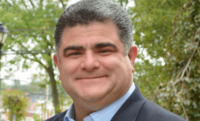Man is smiling for a headshot with a button down and suit.
