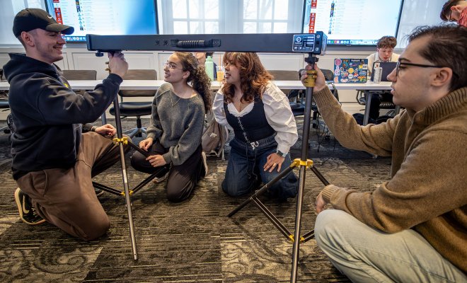 Students and professor setting up film equipment together.