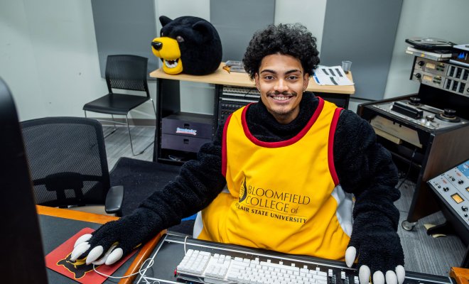 Ethan Garcia wearing part of his Deacon the Bear costume at a soundboard.