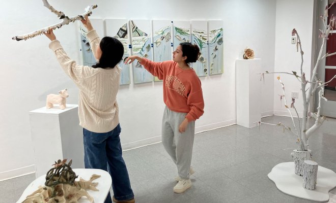 Two students setting up their art exhibit in a museum.