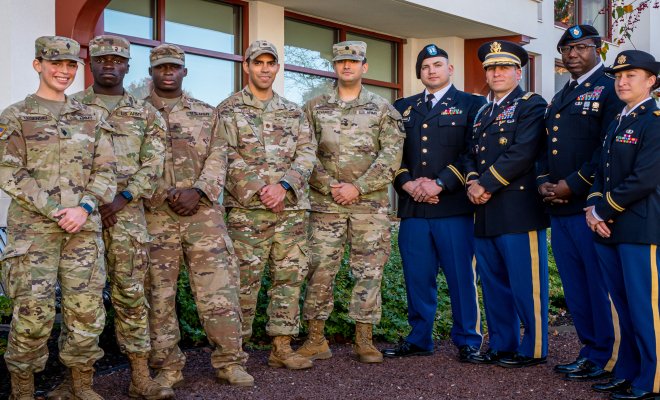 Military personnel posing together with their hands over one another.