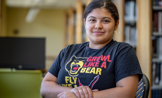 Odyeli Ramos Tobar sits at a table in the campus library.