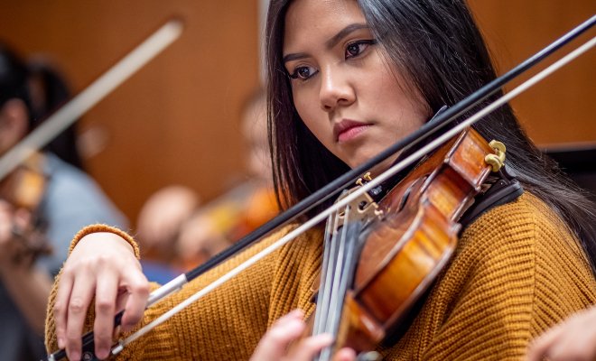 Student in rehearsal playing a Violin.