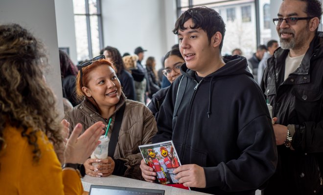 A student in the center, with his parents, talk with a college staff member.