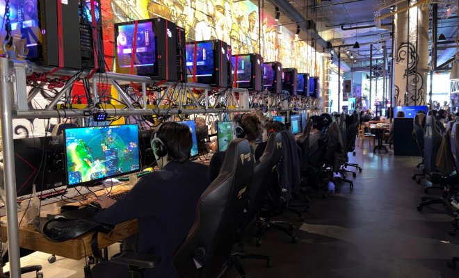 Attendees play video games on computers at a gaming venue.