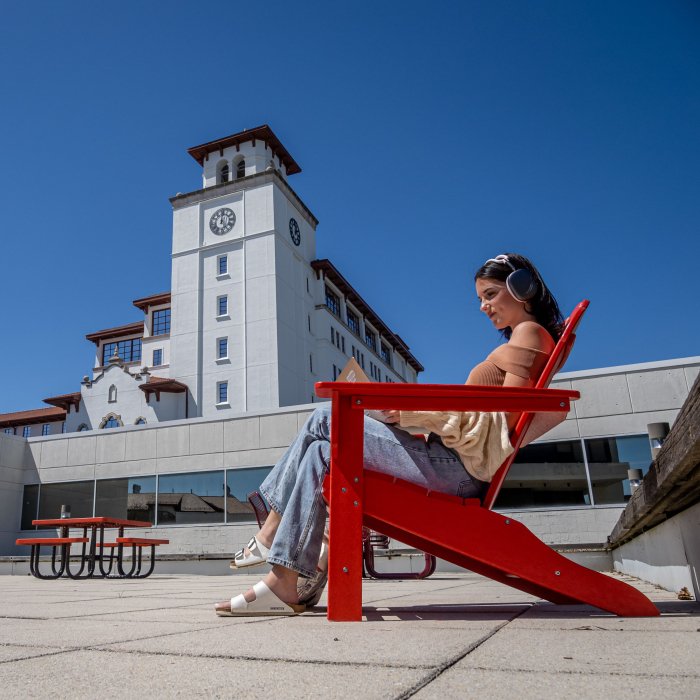 A student in an adirondack chair studies on the roof of the student center annex