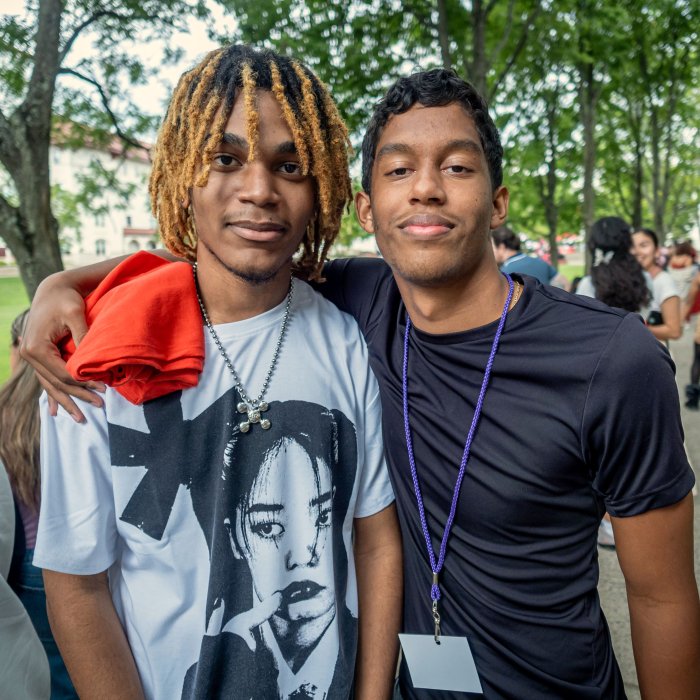 Two first year students at Orientation pause to pose for a photo under the shaded path next to the main quad