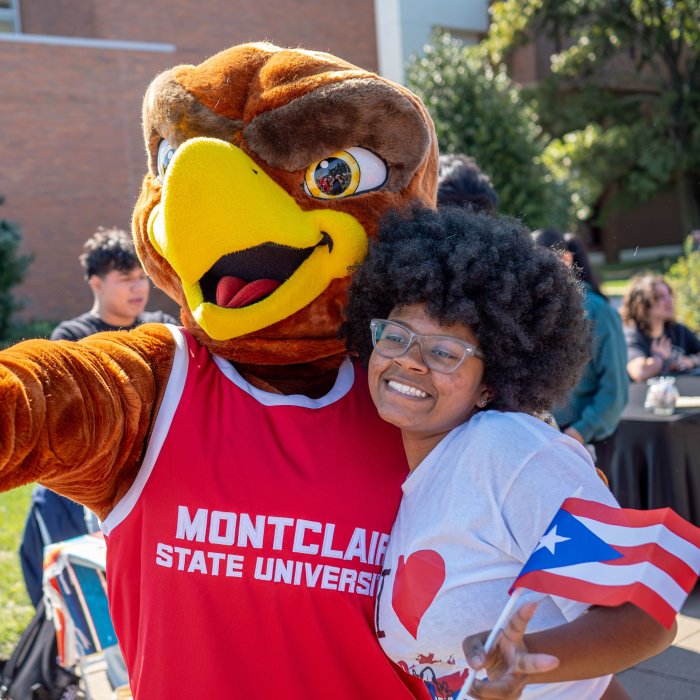 A woman student hugs Rocky the Red Hawk