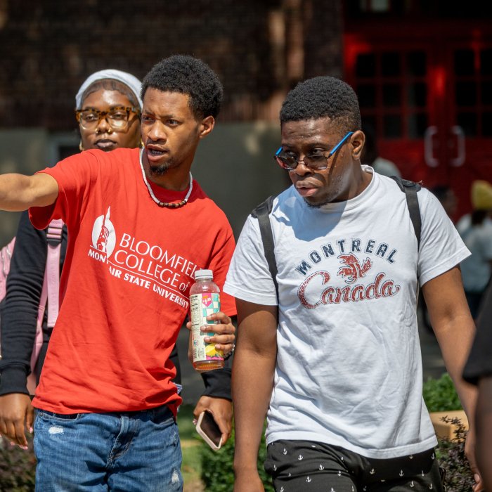A student ambassador in a red Bloomfield College shirt helps a first-year student find his way around at the Bloomfield campus welcome event