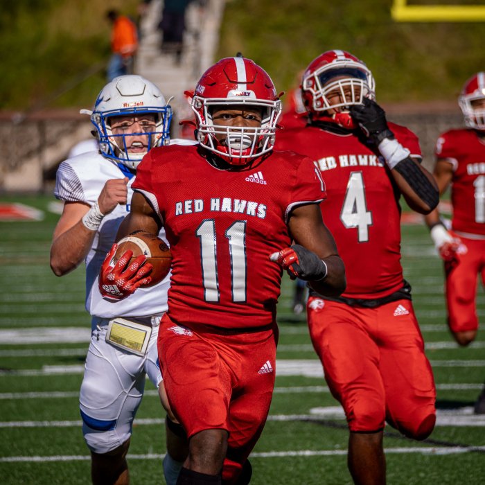 A Montclair football player runs for the endzone with his teammates in the background blocking the defense from pursuing