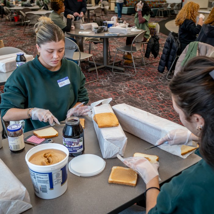 Two women are preparing toast with jelly. 