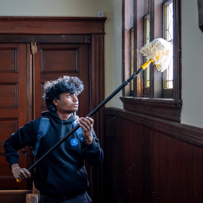 Man is cleaning windows with a cleaning pole. 