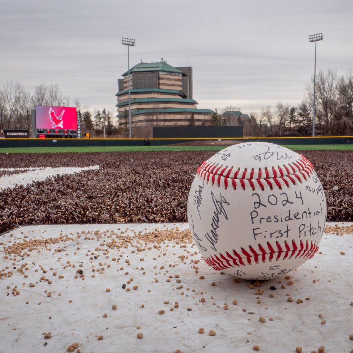 An autographed baseball with the field in the background.