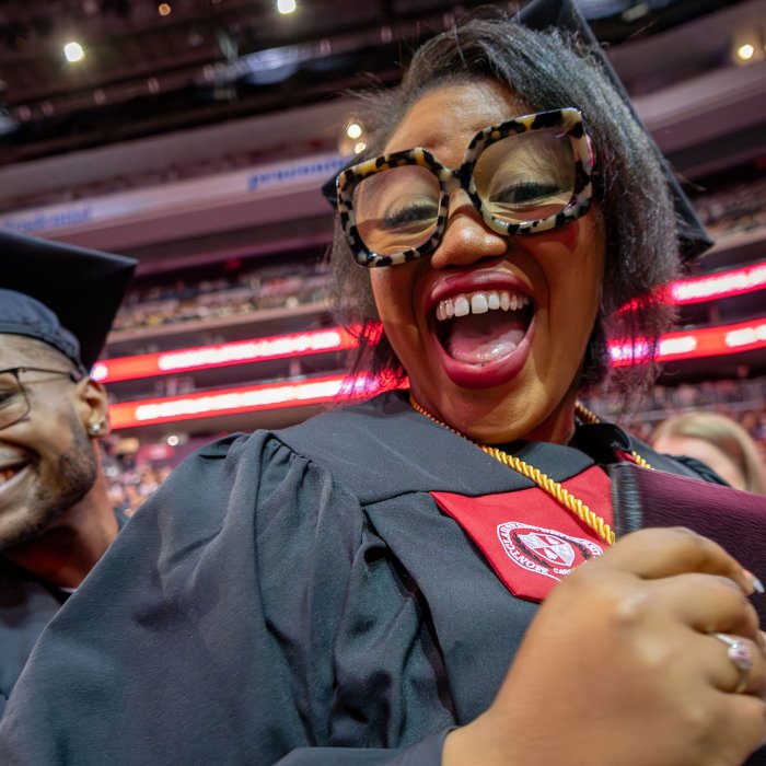Two graduates in caps and gowns smile for the camera