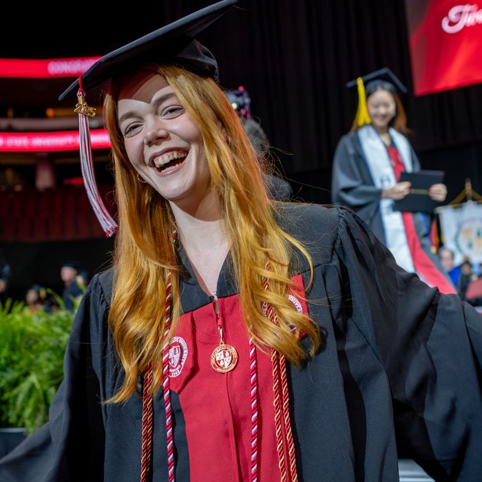 graduate in black cap and gown smiling after receiving diploma
