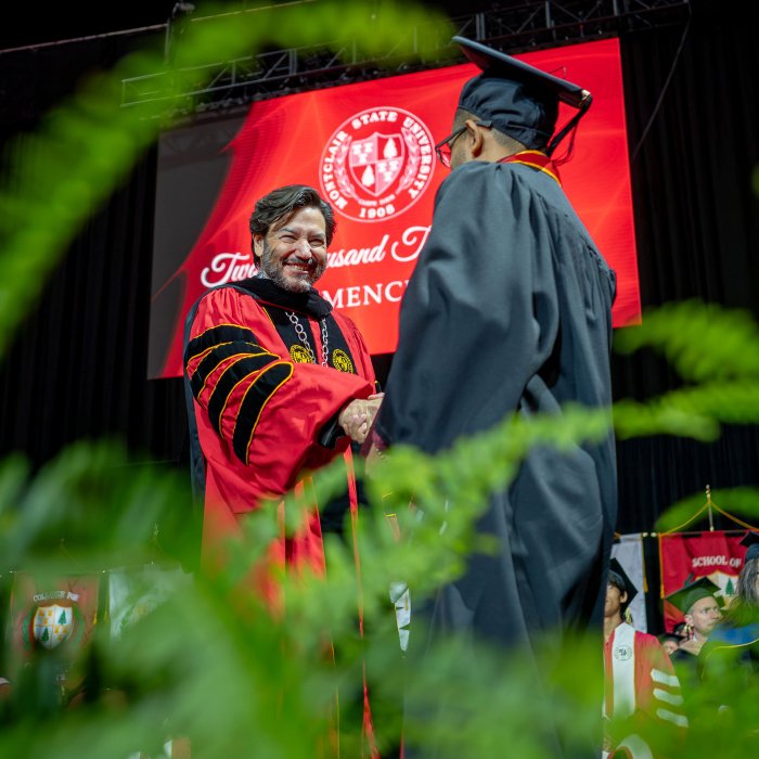 President Koppell shaking hands with a graduate on stage