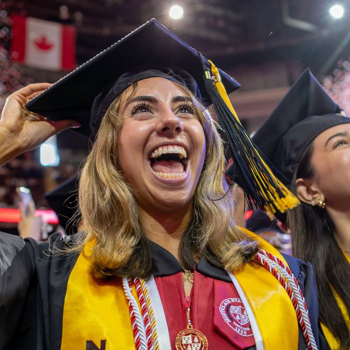 Two graduates smiling and looking toward the stage