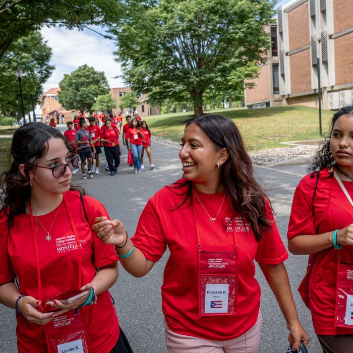 Students are outside walking and conversing with red shirts on.