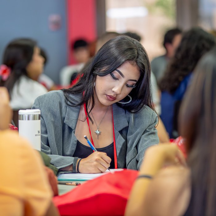 Female student is writing down something on her notebook.