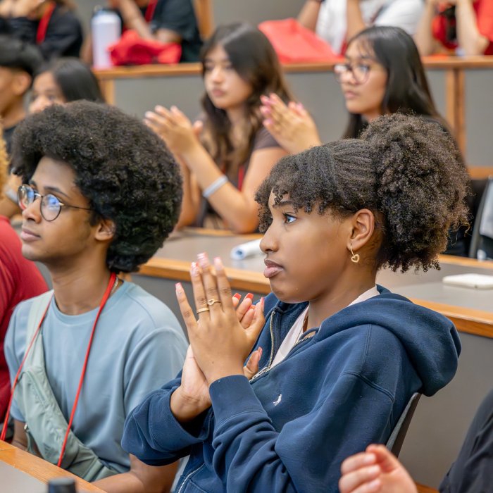 Students in an auditorium style classroom listening attentively. 