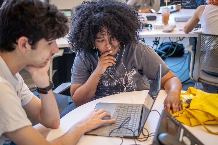 two students working together looking at a laptop