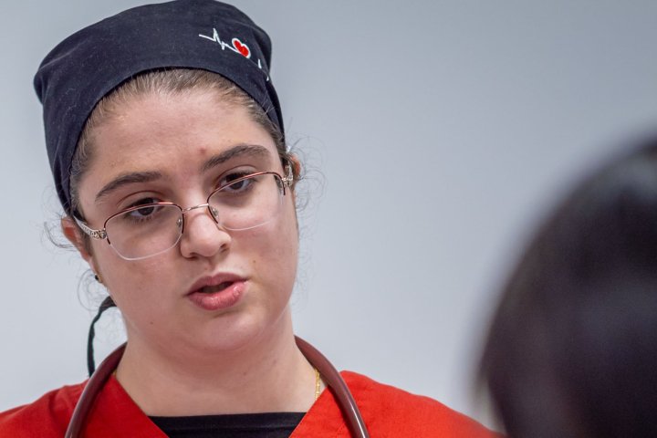 Nursing student is taking notes with a stethoscope around her neck.