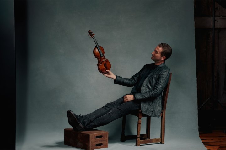 Benjamin Bowman holding violin in chair
