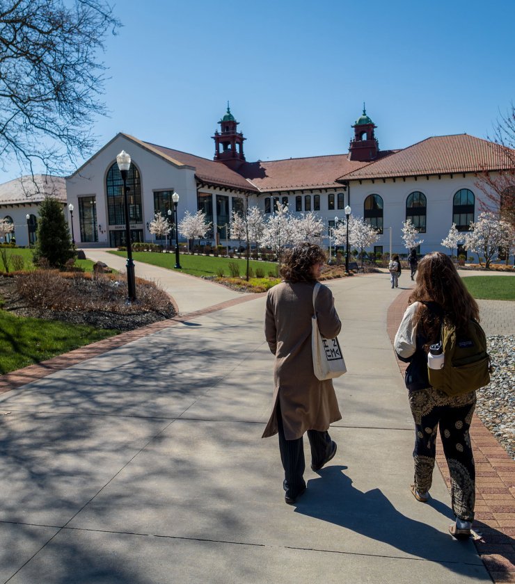 two students walking on campus in spring, various trees blooming