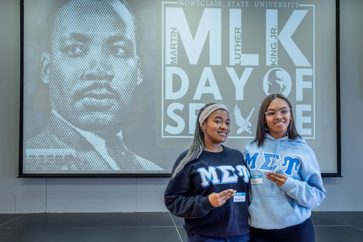 Two sorority members stand before a Martin Luther King Jr.’s Day of Service screen.