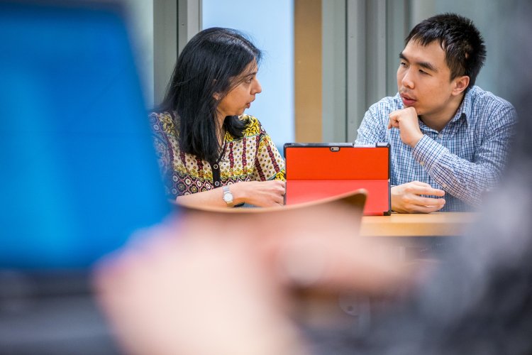 Professor and student seen discussing material on an iPad.